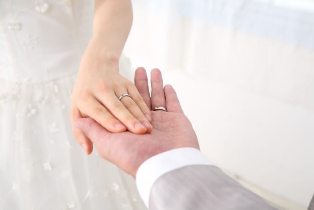 結婚したいか結婚したくないか関わらず、幸せな結婚をイメージした画像。新郎と新婦が手を取り合っている。お互いの手には結婚指輪が光る。